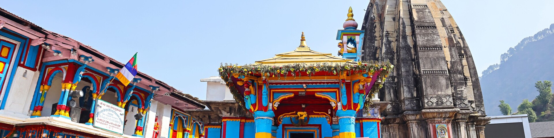 A colorful temple with a golden spire and a stone structure.