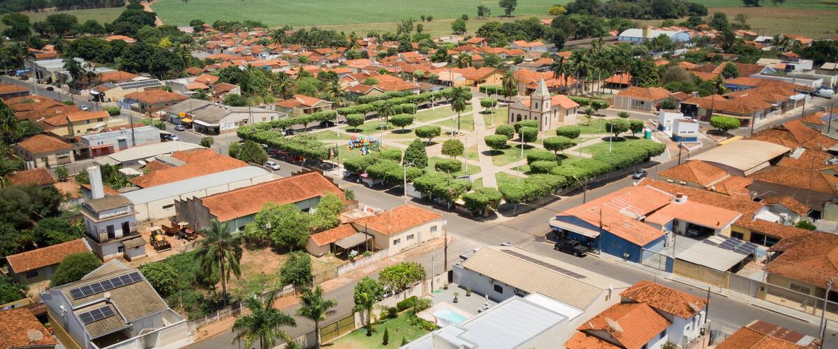 A residential area with red-tiled roofs, green fields, and a central square with a church.