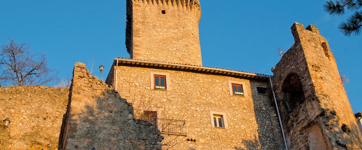 A stone castle with a tall tower and arched windows.