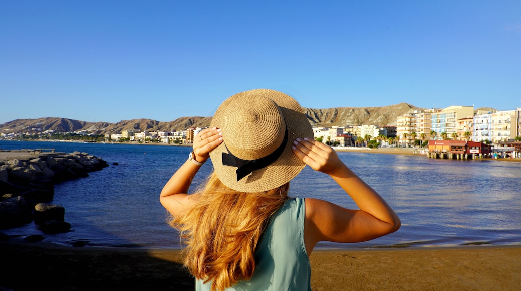 Sunset back view of girl holding straw hat in Crotone city on Calabria coast, Italy