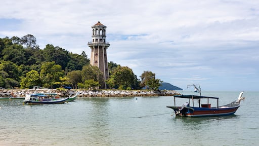 View of perdana quay with a lighthouse and boats by the serene coast, Kuala Teriang, Malaysia.