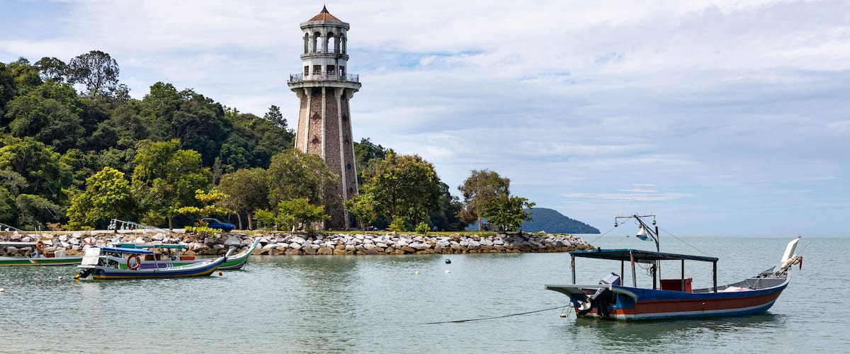 A coastal scene with a lighthouse, boats, and lush greenery.
