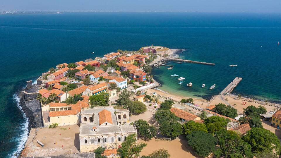 A coastal town with historic buildings, a beach, and boats.