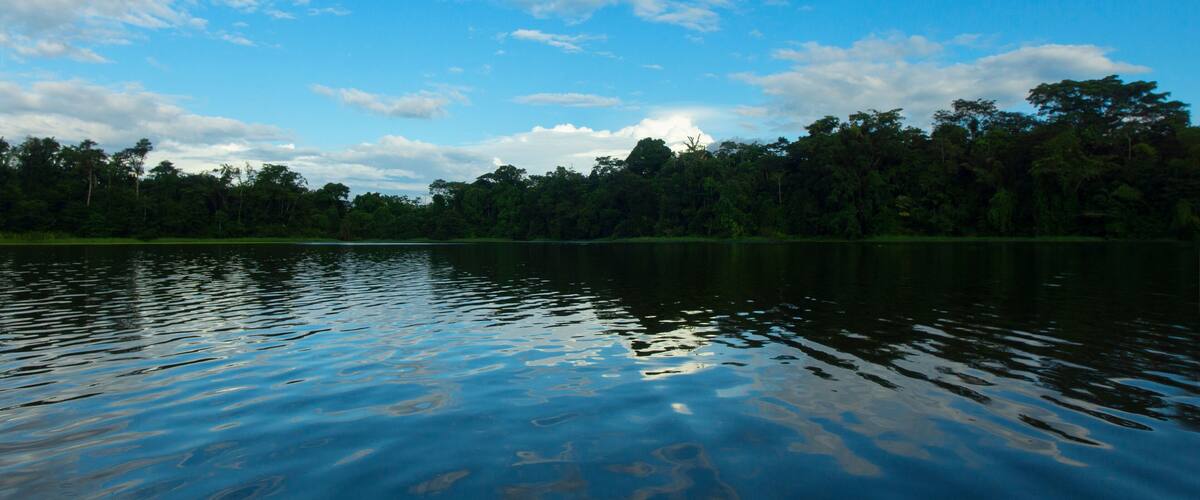 A calm lake with reflections of the sky and trees.