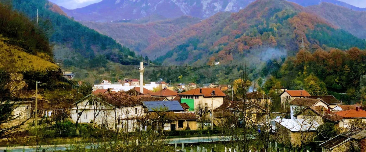 A village nestled in a valley with mountains in the background.