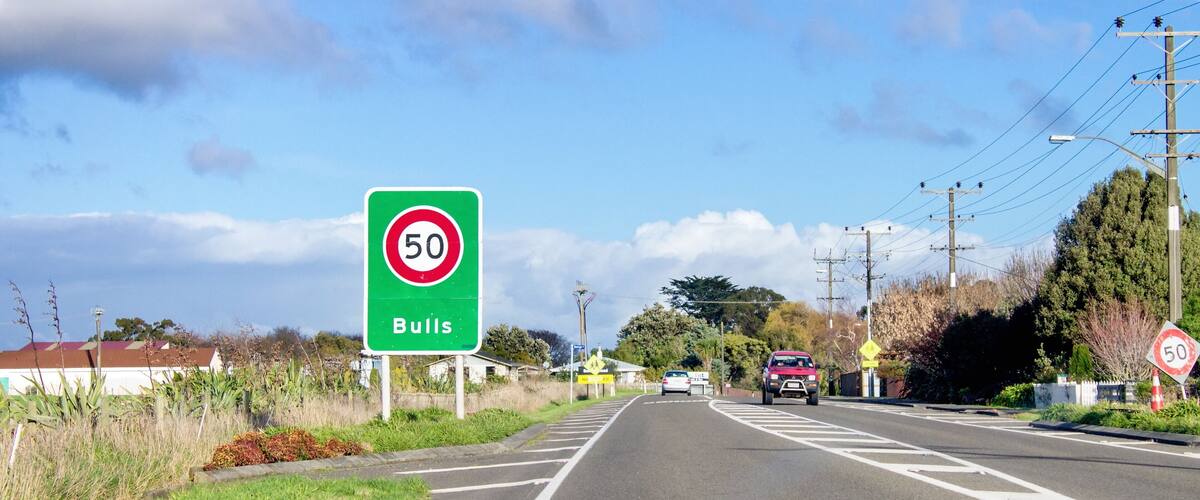 A road with a speed limit sign of 50, a directional sign for Bulls, and a zebra crossing.