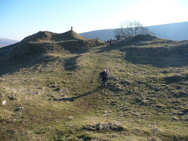 A hilly landscape with a person walking on a trail.