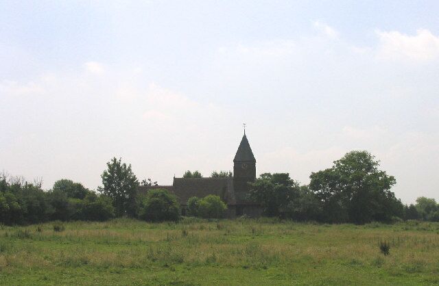 A church with a tall steeple in a grassy field.
