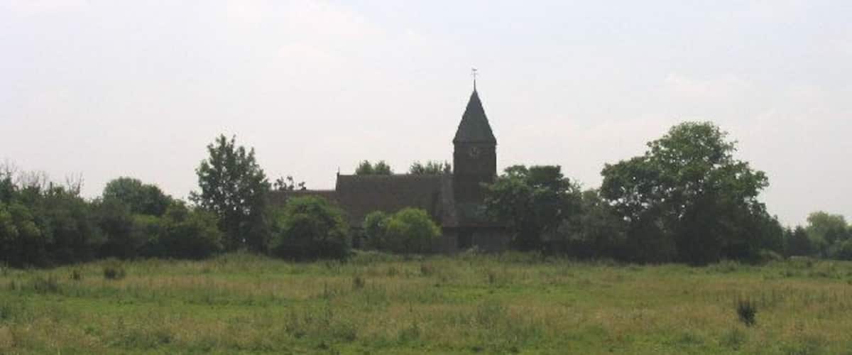 A church with a tall steeple in a grassy field.