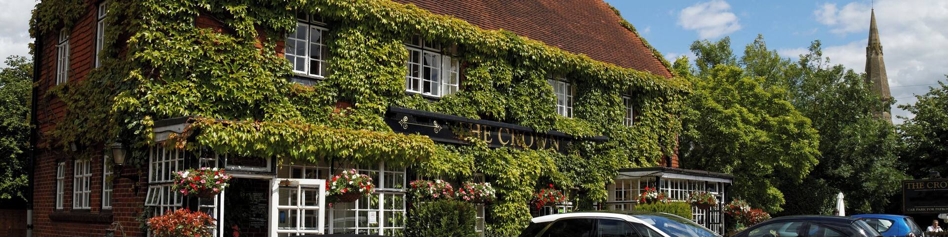 The Crown public house covered by Boston Ivy, with car park including a Mini Cooper and a Citroën C4 Picasso, at 45 Newgate Street Village (name of road), at Newgate Street, in the civil parish of Hatfield, and the Borough of Welwyn Hatfield, Hertfordshire, England. Camera: Canon EOS 6D with Canon EF 24-105mm F4L IS USM lens. Software: file lens-corrected and optimized with DxO OpticsPro 10 Elite and Viewpoint 2, and further optimized with Adobe Photoshop CS2.
