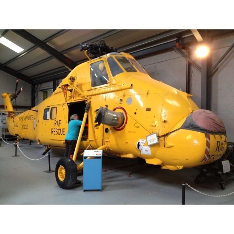 A yellow RAF rescue helicopter with a person boarding it.