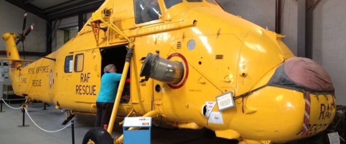 A yellow RAF rescue helicopter with a person boarding it.