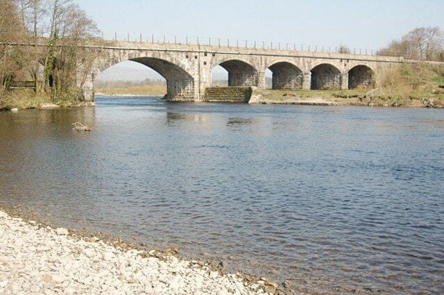 Un puente de piedra con tres arcos sobre un río.