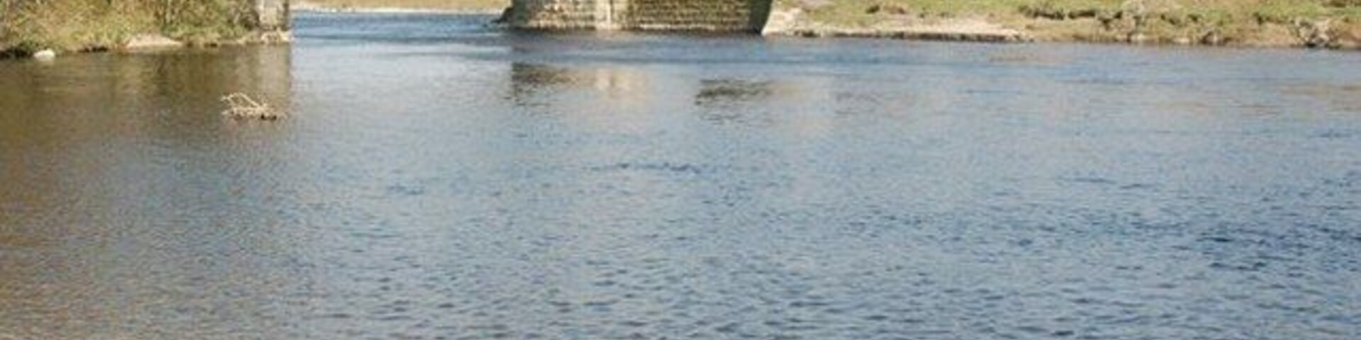 Un puente de piedra con tres arcos sobre un río.