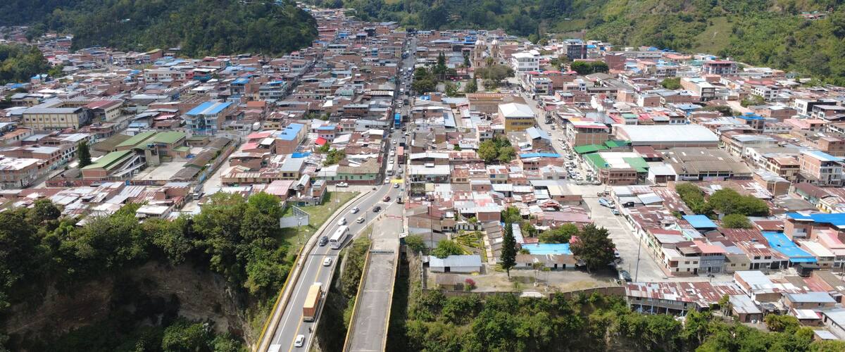 A densely packed town with a central road, surrounded by hills and greenery.