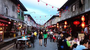 A bustling street lined with traditional wooden buildings, adorned with red lanterns.