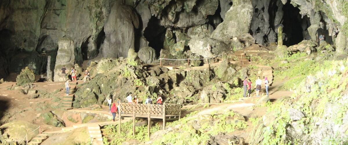 A cave entrance with a wooden walkway and people exploring the rocky interior.