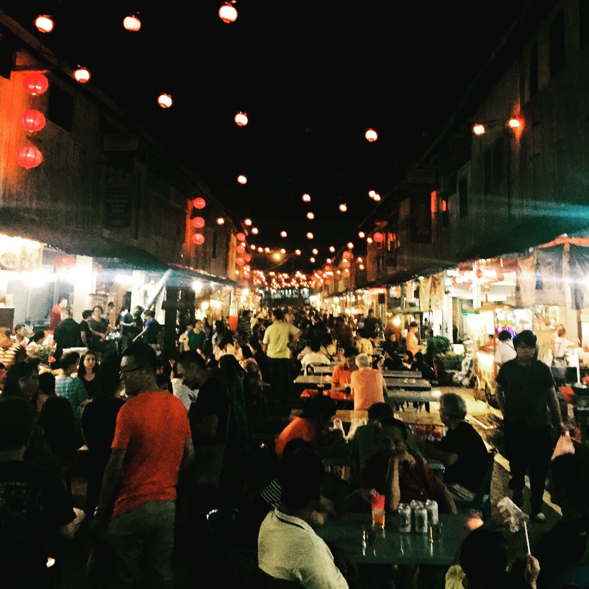 A crowded street market at night with numerous stalls and people.