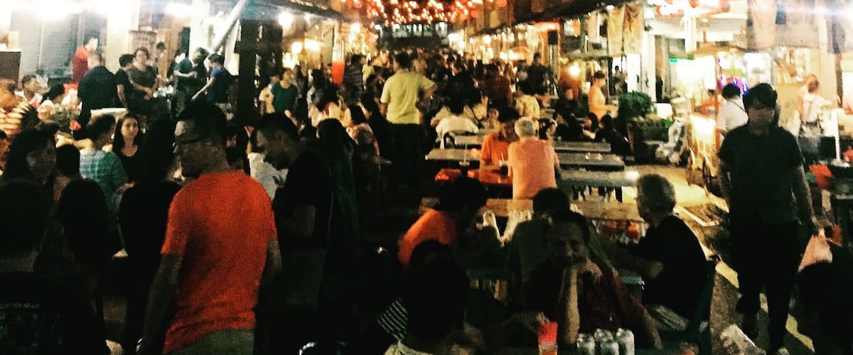 A crowded street market at night with numerous stalls and people.