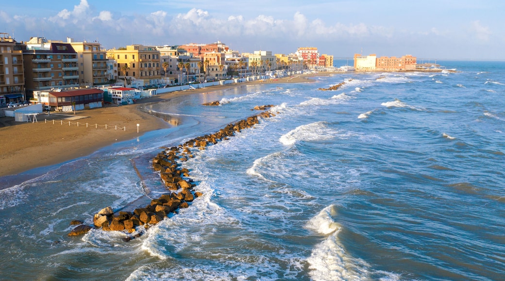 Aerial view of the coast of Anzio, a small sea town near Rome, in Italy. There is no one on the beach on this cold spring day. The blue sea with its waves is rough. In the sky there are some clouds.
