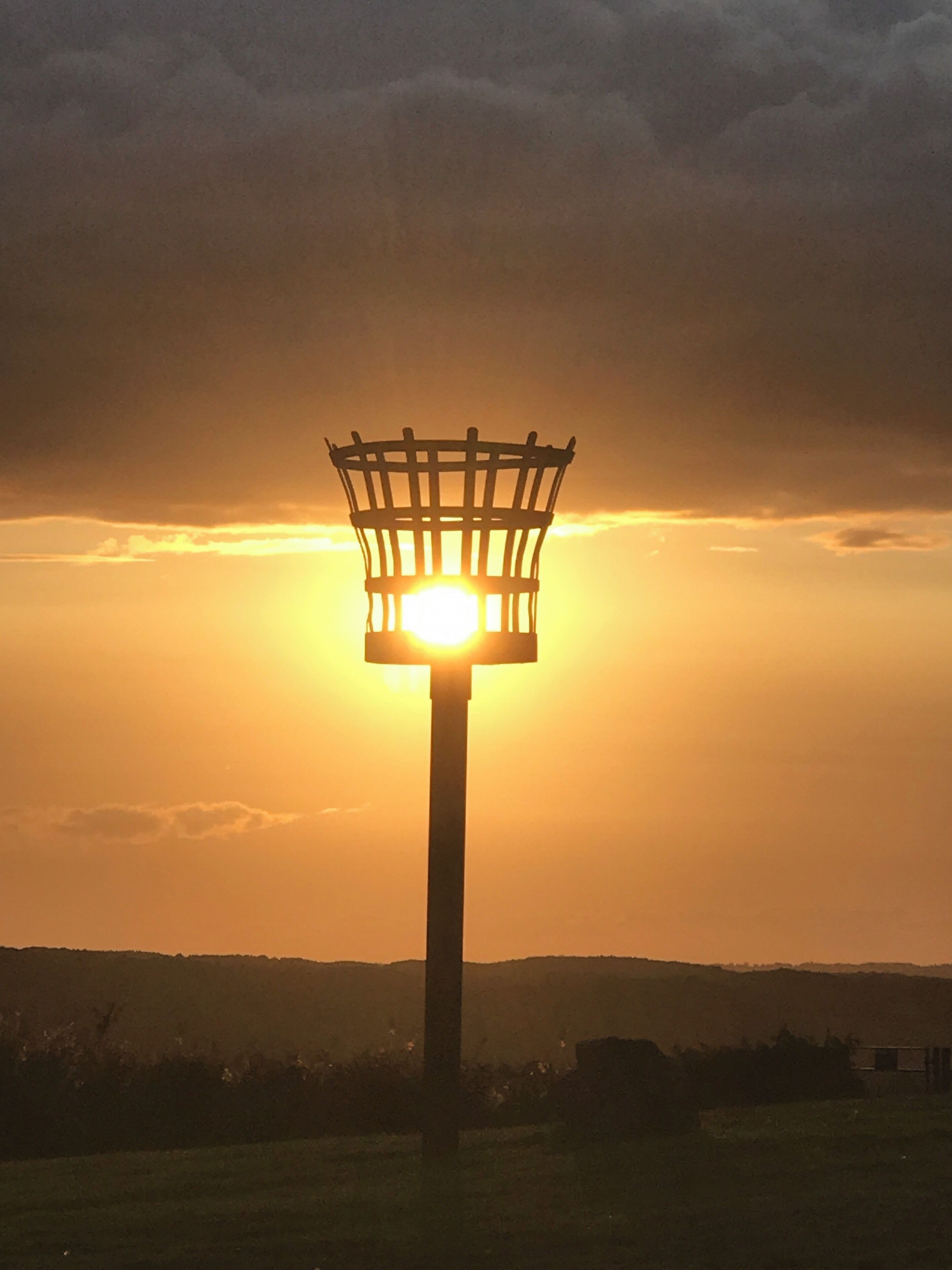 A street lamp silhouetted against a sunset with a clear sky.