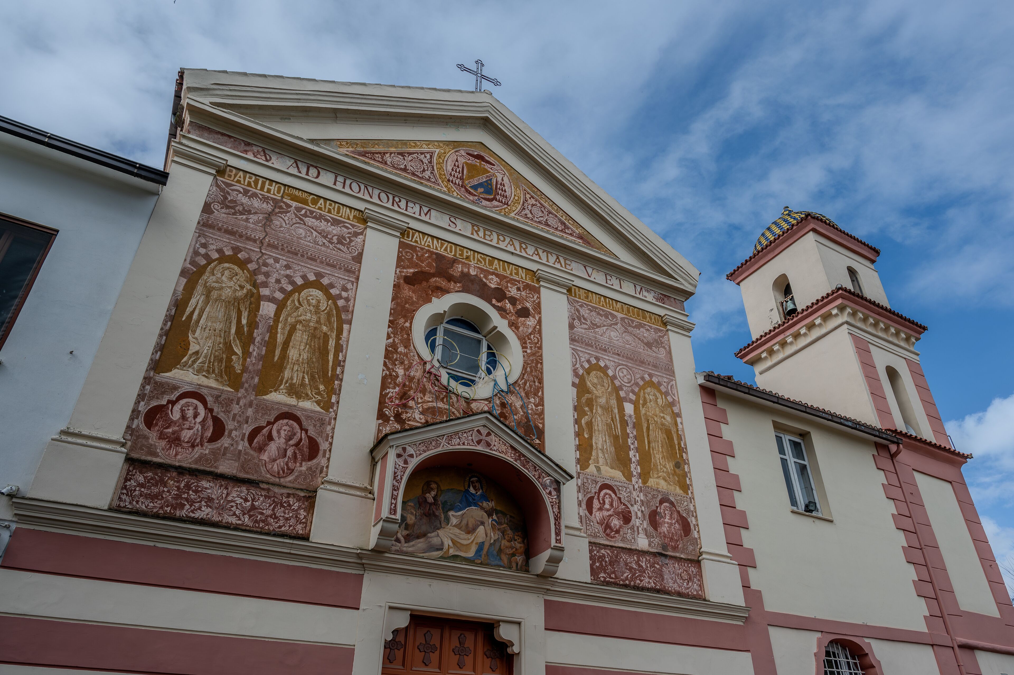 A church facade with detailed frescoes and a bell tower.