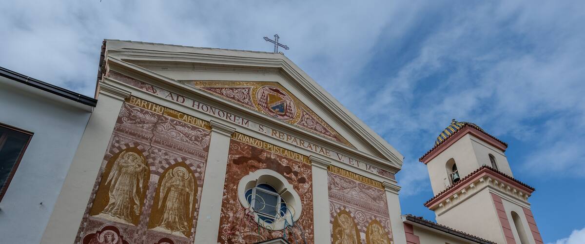 A church facade with detailed frescoes and a bell tower.