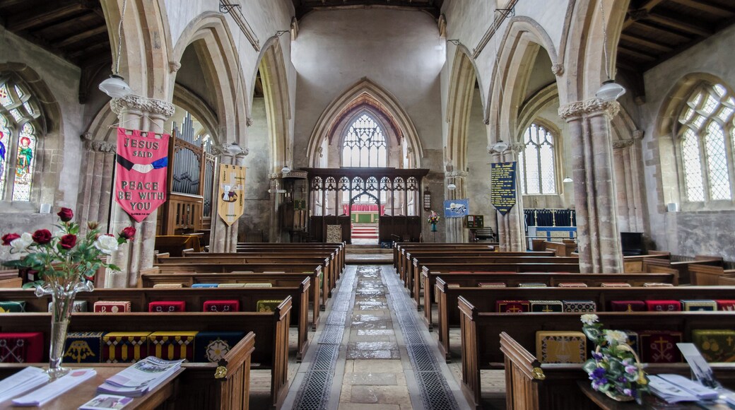 The church dates from circa 1300, and is built from ashlar with the lead roofs. The church is a cruciform plan with a west tower and spire, nave with north and south aisles, south porch, transepts, chancel and north vestry. The tower is of four stages, the two lower of circa 1300, the two upper of circa 1500. On the east side of the nave the original steeply pitched roofline is visible. The tower has ornate pinnacles and projecting gargoyles, the octagonal spire is 15th century with lucarnes, Crockets and finial. The nave has clerestory windows of three lights. There are moulded eaves with corbel heads above,and a frieze of shields, battlements and ornate pinnacles. The north aisle has an early 14th century west window and on the roof is a small bell turret,the north transept has early 14th century window of three lights. The chancel is 15th century and was restored in the 19th C. It has two large windows on both north and south sides each of three lights. There are hood moulds and grotesque animal label stops.There is a large pointed east window of five lights with perpendicular tracery. The original roofline of the chancel is visible on the east end of the nave. The south transept was probably remodelled in the 15th century from a detached lady Chapel built circa 1275. The west side of the transept has 14th century windows with head label stops. The porch is 14th century and has 15th century ornamentation, it has projecting gargoyles and ornate pinnacles. It contains stone benches and a corbel that once supported a roof, one is dated 1631. The 14th century west door has foliated capitals with elaborate finials. The nave has three bays, with piers from circa 1300. The south wall of the south transept has three 13th century sedilia and two aumbries. The chancel arch is from the 14th century and has caryatid figures. There is a 14th century screen which was restored in the 19th century. There is a 14th century hexagonal font with ornate Gables and pinnacles. The church contains various small 18th and 19th-century monuments. The church has recently undergone much restoration work including work to the spire, tower, bells, roof, windows and a new boiler system.