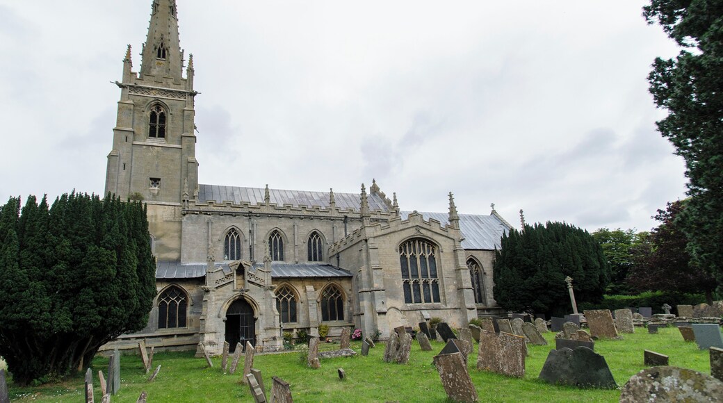The church dates from circa 1300, and is built from ashlar with the lead roofs. The church is a cruciform plan with a west tower and spire, nave with north and south aisles, south porch, transepts, chancel and north vestry. The tower is of four stages, the two lower of circa 1300, the two upper of circa 1500. On the east side of the nave the original steeply pitched roofline is visible. The tower has ornate pinnacles and projecting gargoyles, the octagonal spire is 15th century with lucarnes, Crockets and finial. The nave has clerestory windows of three lights. There are moulded eaves with corbel heads above,and a frieze of shields, battlements and ornate pinnacles. The north aisle has an early 14th century west window and on the roof is a small bell turret,the north transept has early 14th century window of three lights. The chancel is 15th century and was restored in the 19th C. It has two large windows on both north and south sides each of three lights. There are hood moulds and grotesque animal label stops.There is a large pointed east window of five lights with perpendicular tracery. The original roofline of the chancel is visible on the east end of the nave. The south transept was probably remodelled in the 15th century from a detached lady Chapel built circa 1275. The west side of the transept has 14th century windows with head label stops. The porch is 14th century and has 15th century ornamentation, it has projecting gargoyles and ornate pinnacles. It contains stone benches and a corbel that once supported a roof, one is dated 1631. The 14th century west door has foliated capitals with elaborate finials. The nave has three bays, with piers from circa 1300. The south wall of the south transept has three 13th century sedilia and two aumbries. The chancel arch is from the 14th century and has caryatid figures. There is a 14th century screen which was restored in the 19th century. There is a 14th century hexagonal font with ornate Gables and pinnacles. The church contains various small 18th and 19th-century monuments. The church has recently undergone much restoration work including work to the spire, tower, bells, roof, windows and a new boiler system.