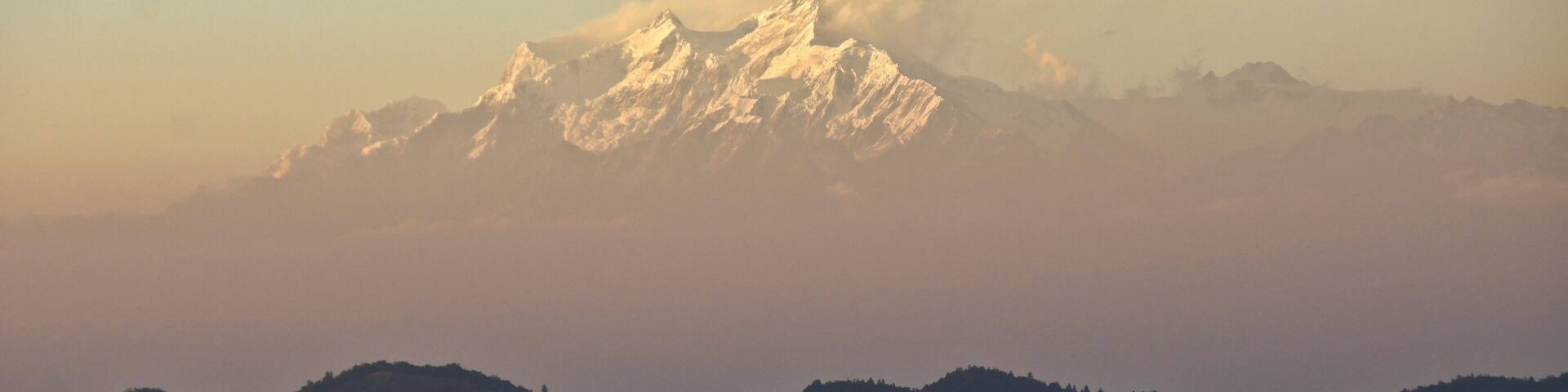 Foothills, valleys, and snow-capped peaks of Himalaya mountain range in late-afternoon light and mist, viewed from Daman, Nepal