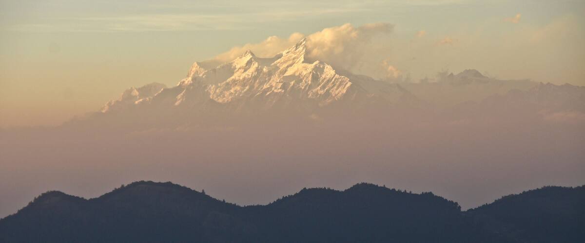 A mountain range with snow-capped peaks and a forested foreground.