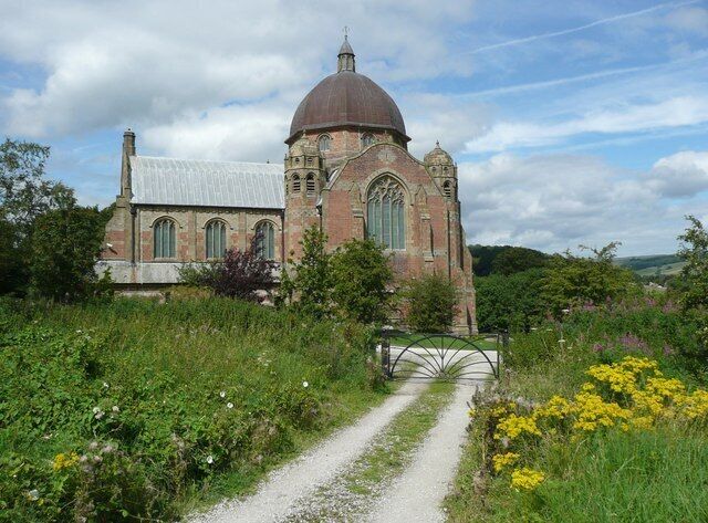 A historic church with a dome, surrounded by lush greenery and a gravel path.