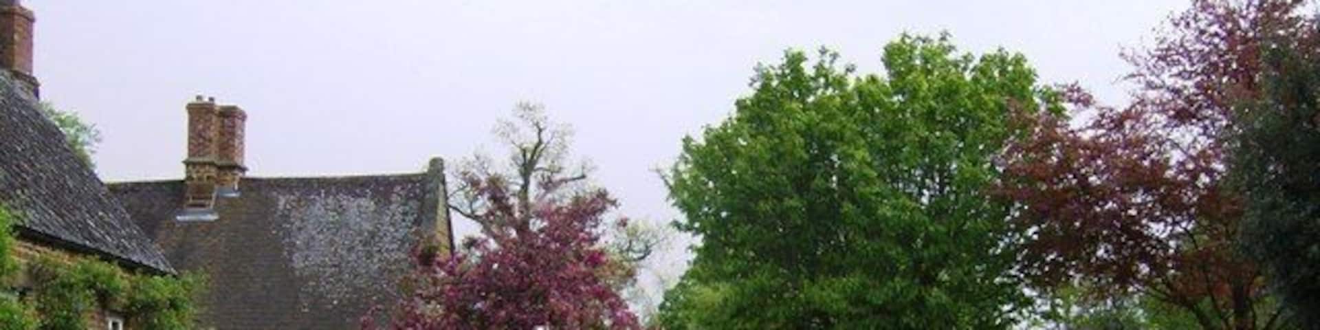 The Green, Eydon, Northamptonshire. The gates ahead are the entrance to Eydon Hall. The second house on the left is Eydon Hall farmhouse.