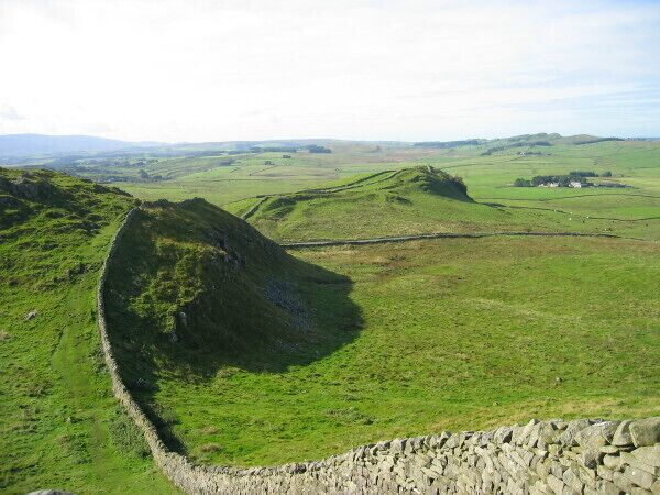 A stone wall and grassy hills in a rural landscape.