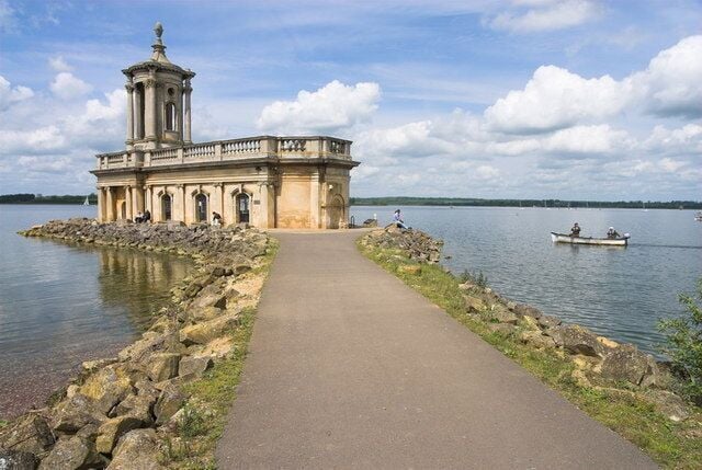 A historic building with a tower by a calm lake.