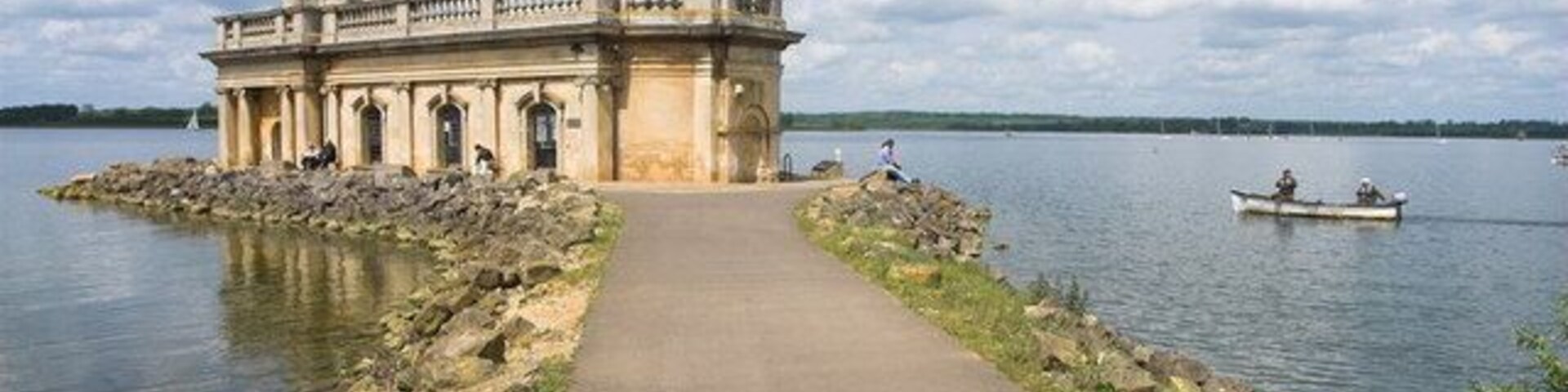 Un edificio histórico con una torre junto a un lago tranquilo.