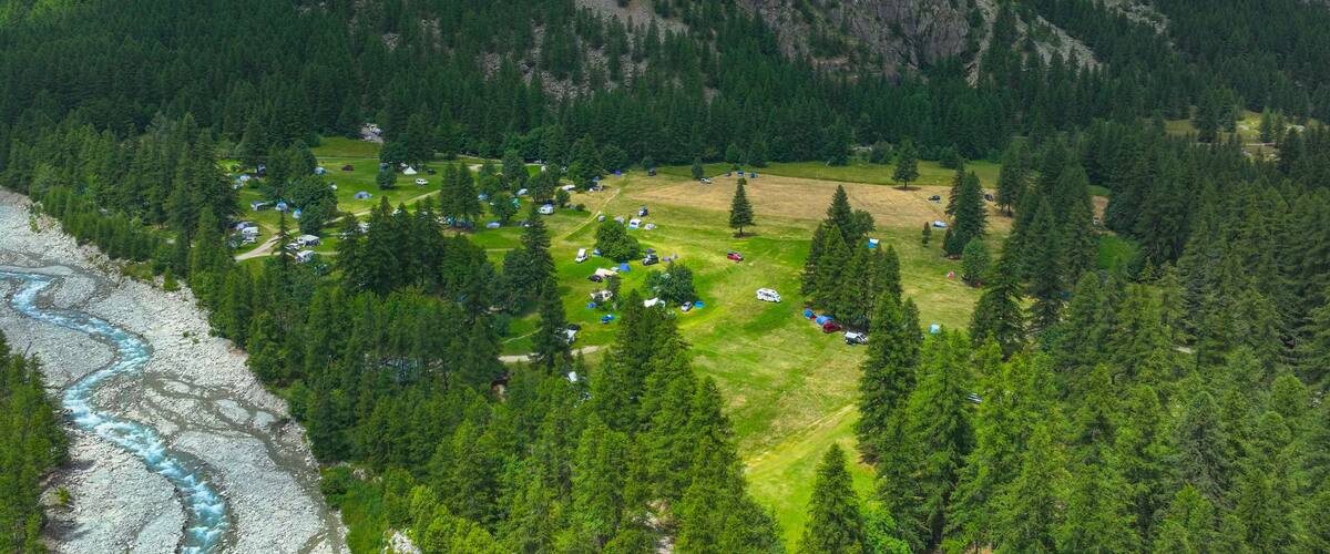 An aerial view of a campsite surrounded by dense forests and mountains.