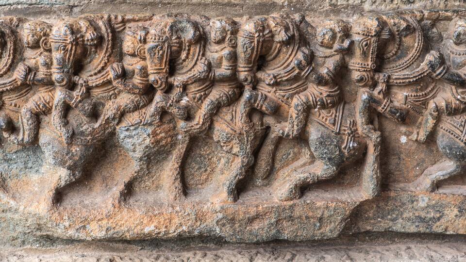 A detailed stone carving of a procession of figures on horseback.