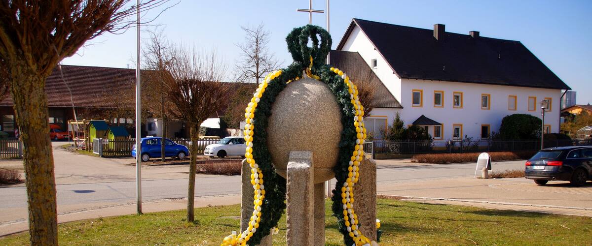 A stone sculpture with yellow and white balloons, a church, and a residential building.