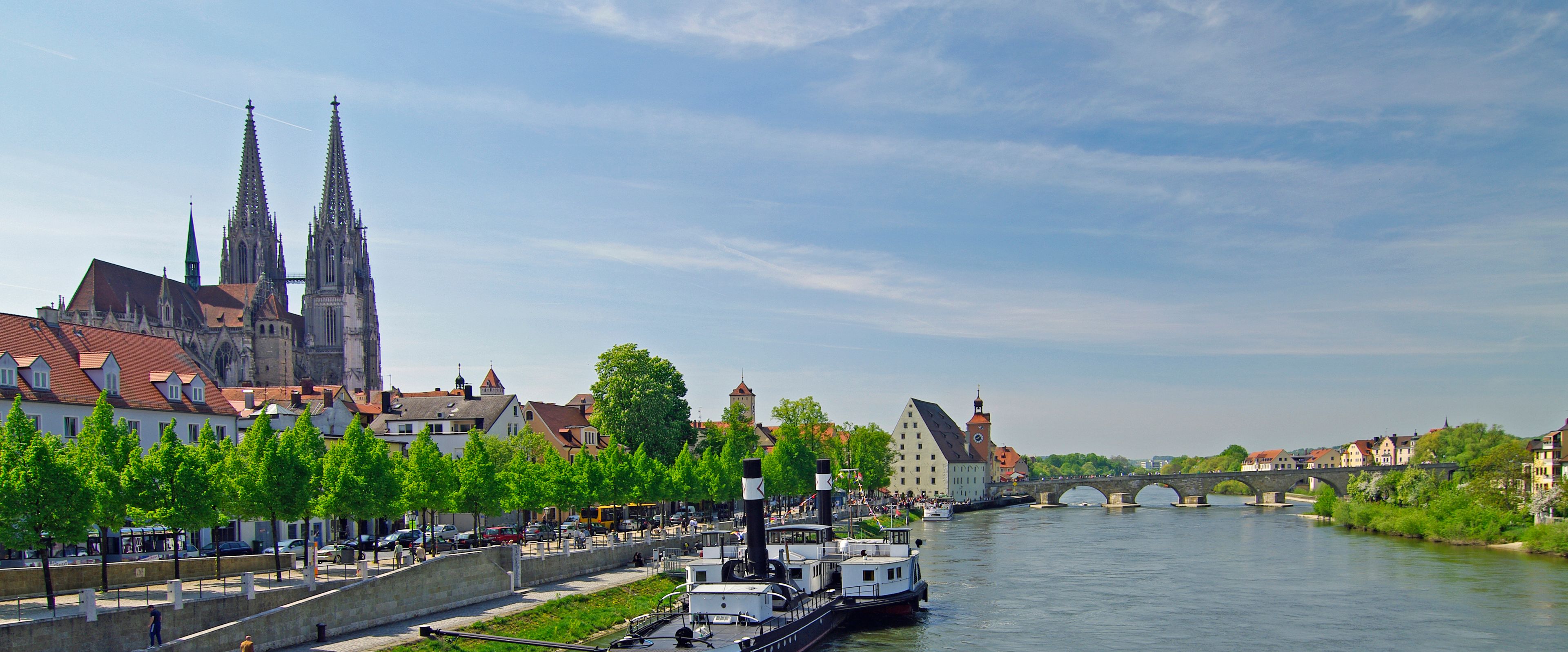 A river with a boat, a bridge, and a cathedral with spires.