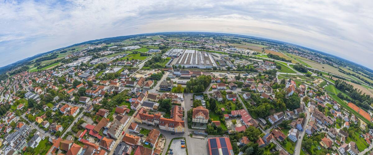 An aerial view of a town with residential areas, industrial buildings, and green fields.