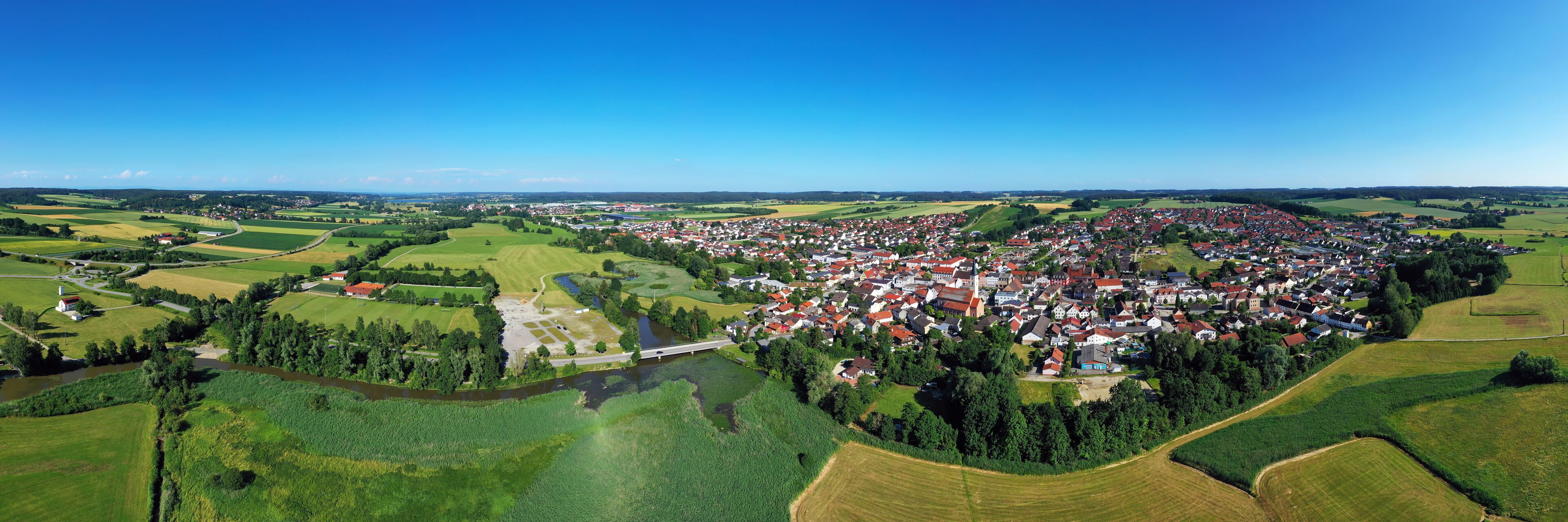 A rural landscape with a river, fields, and a small village.