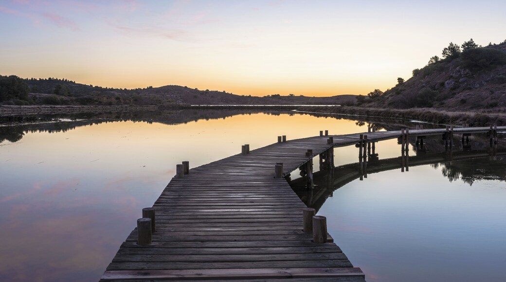 Hills, trees and footbridge reflected in the former salt ponds of Peyriac-de-Mer, Aude, France