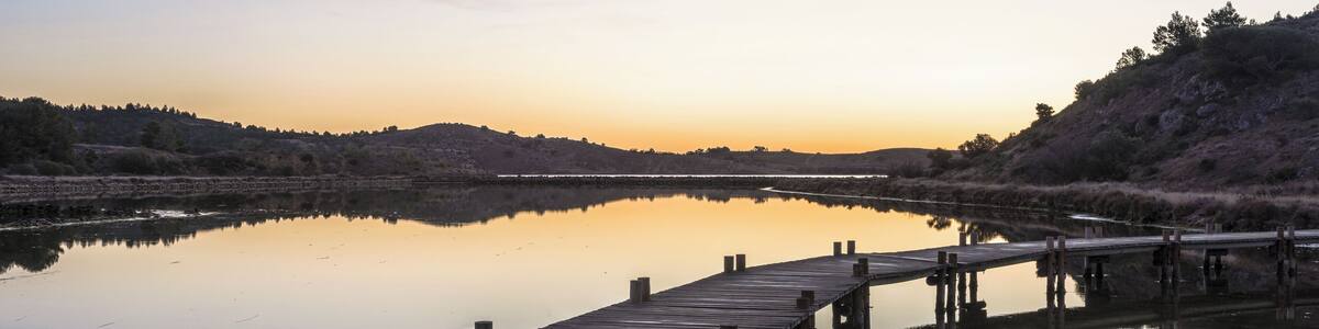 Hills, trees and footbridge reflected in the former salt ponds of Peyriac-de-Mer, Aude, France