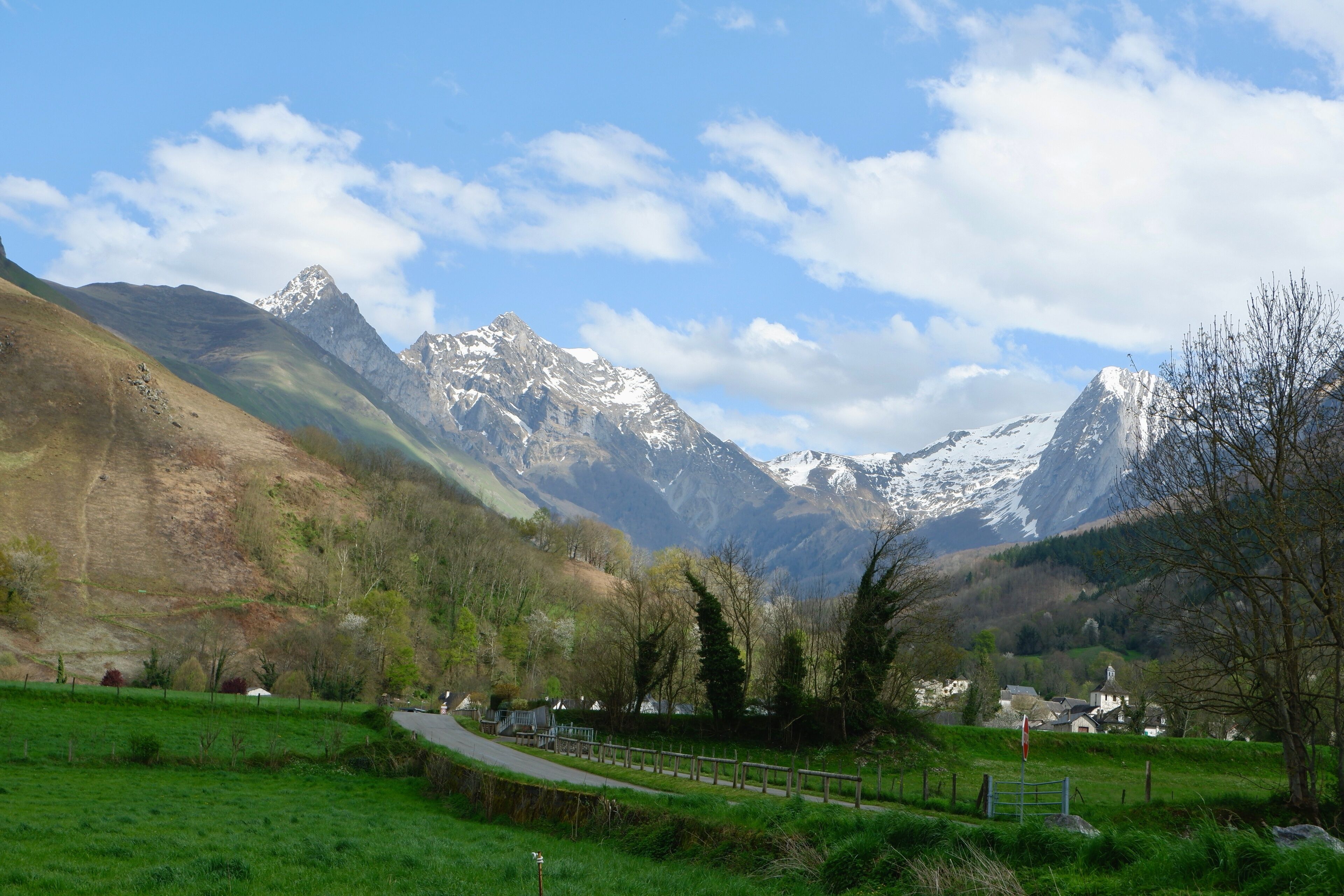 A mountain landscape with a road, green fields, and a small village.