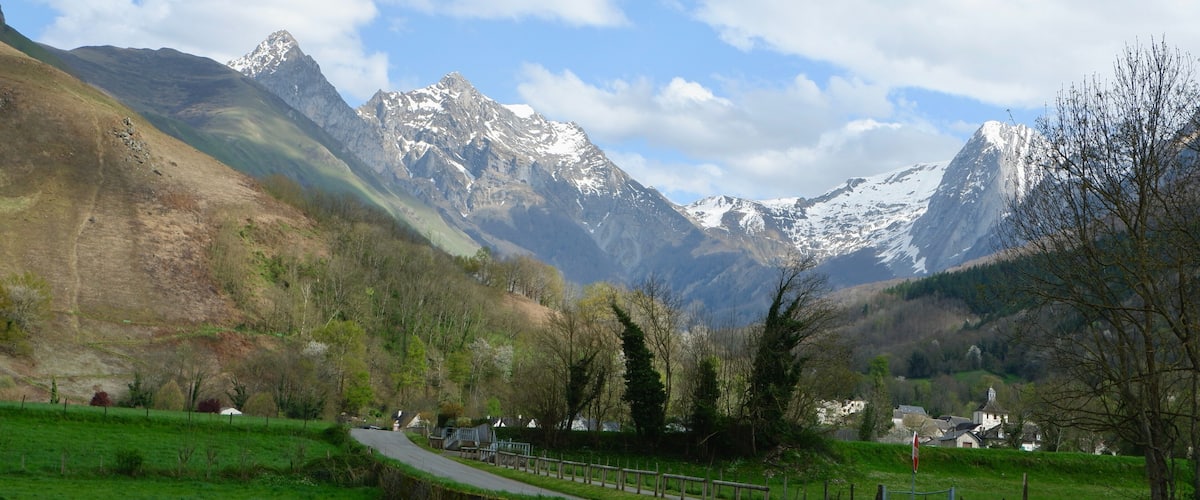 A mountain landscape with a road, green fields, and a small village.