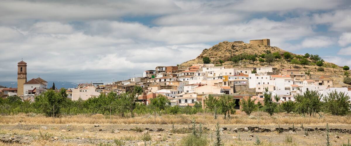 A town with a prominent hilltop fortress, a church with a bell tower, and a dense cluster of buildings.
