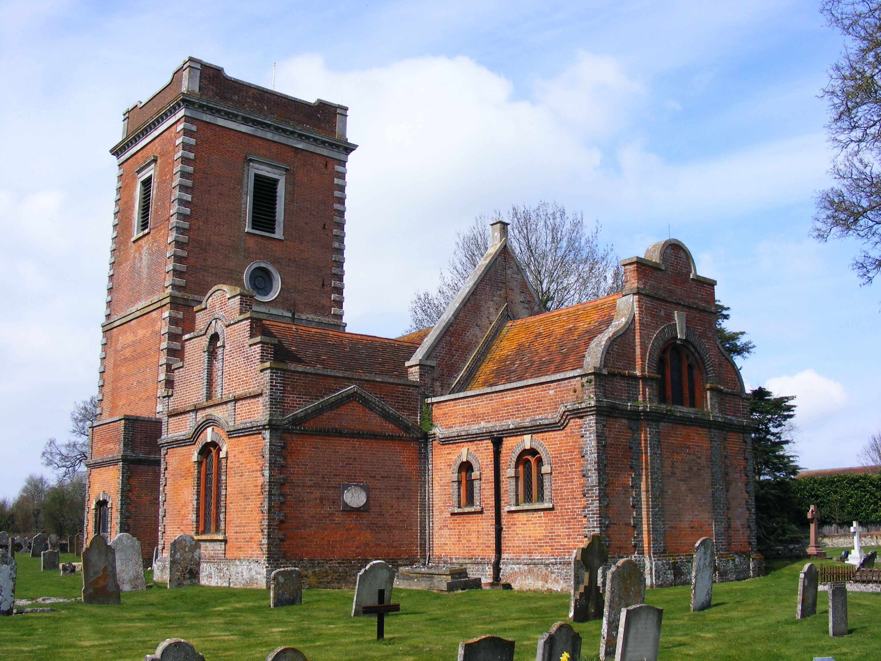A historic church with a prominent tower and a cemetery in front.