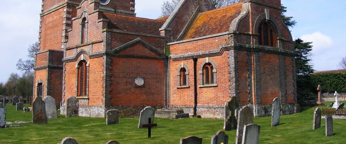 A historic church with a prominent tower and a cemetery in front.