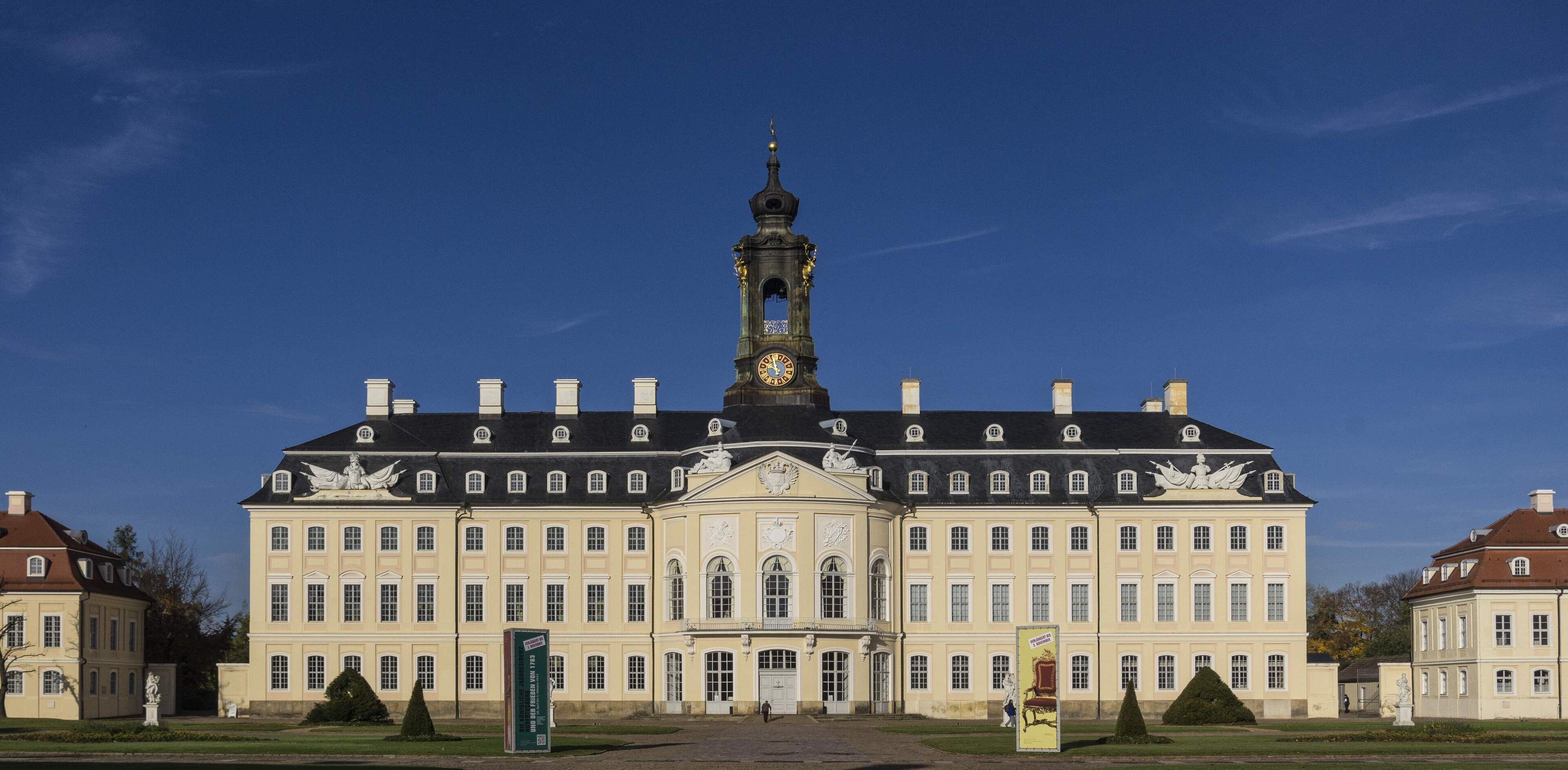 A large stately building with a prominent clock tower, symmetrical windows, and statues on the facade.